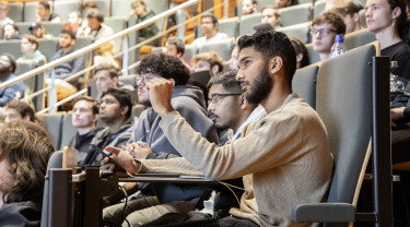 Studenten zitten in een hoorcollegezaal te luisteren naar een spreker